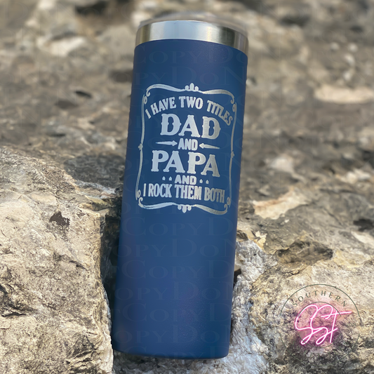 20oz skinny straight powder coated tumbler in the color navy laser engraved saying I have two titles dad and papa and I rock them both