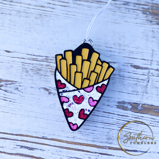 vehicle air freshener in the shape of french fries wrapped in sparkling paper with red and pink hearts