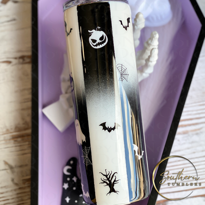 20oz skinny tumbler painted half black and half white decorated with bats, spiders, and cats saying never trust the living which also glows in the dark