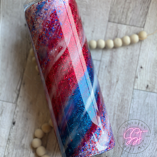 20oz skinny straight tumbler decorated with red white and blue glitter with red white and blue mica powder creating a milky way effect