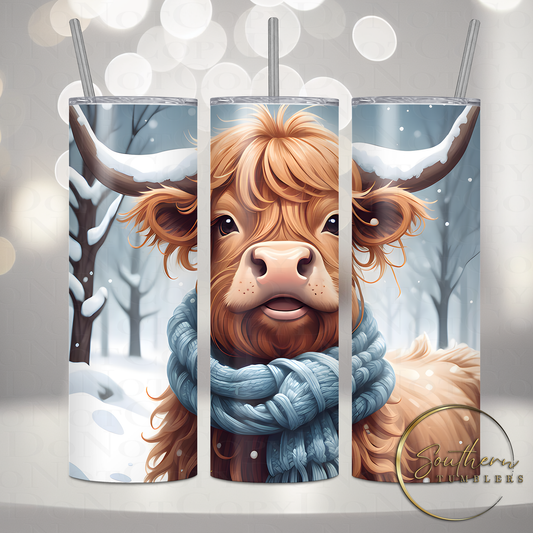 20oz skinny stainless steel sublimated tumbler decorated with an adorable highland cow wearing a blue scarf in a snow field 