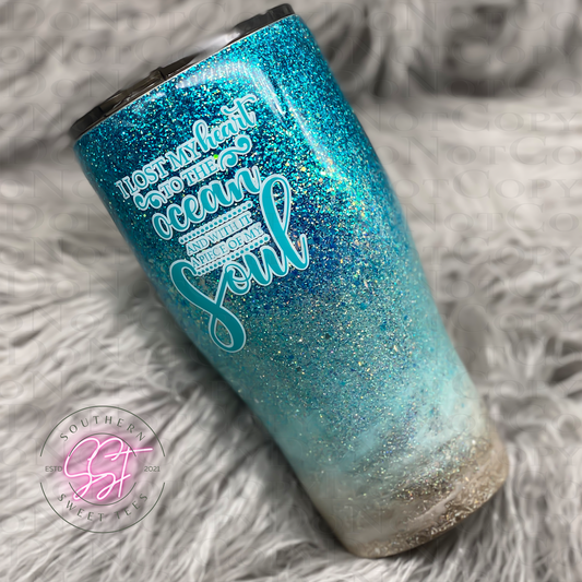 20oz modern curved tumbler decorated with tiffany blue and teal glitters to resemble the depths of the ocean saying I lost my heart to the ocean and with it a piece of my soul