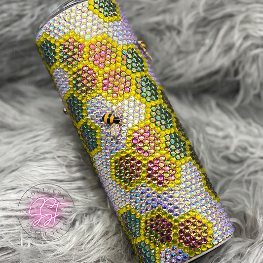Rhinestone 20oz skinny tumbler designed with color shifting pink to yellow to green bee hives outlined in yellow filled in with color shifting crystal to yellow rhinestones with added bee's